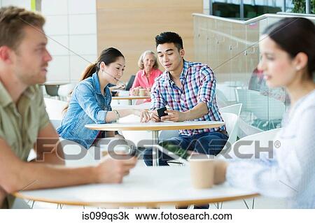 Young couple in canteen area, looking at cellphone View Large Photo Image Stock Image - Young couple in canteen area, looking at cellphone. Fotosearch