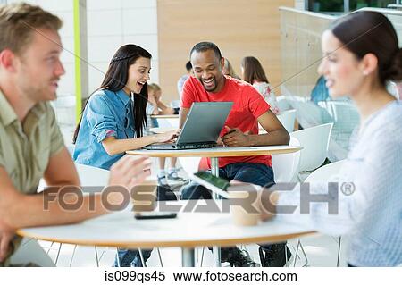 Stock Photography - Young couple in canteen area, looking at laptop. Fotosearch