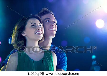 Young couple looking up at lights View Large Photo Image Stock Photograph - Young couple looking up at lights. Fotosearch