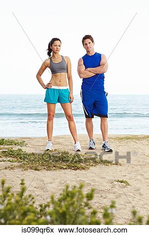 Young couple on beach wearing sportswear, portrait View Large Photo Image Stock Photo - Young couple on beach wearing sportswear, portrait. Fotosearch