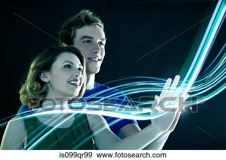 Stock Photo - Young couple touching streams of light. Fotosearch