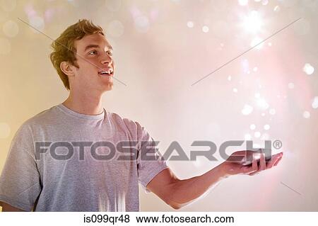 Young man looking at lights coming from cellphone View Large Photo Image Stock Photo - Young man looking at lights coming from cellphone. Fotosearch