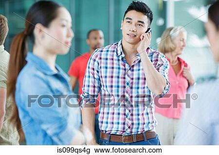 Stock Image - Young man on cellphone in crowd. Fotosearch