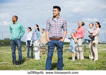 Stock Image - Young man standing in front of group of people outdoors. Fotosearch