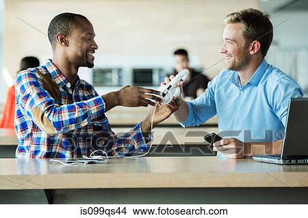 Picture - Young men sharing headphones. Fotosearch