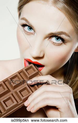 Picture - Young woman biting chocolate. Fotosearch