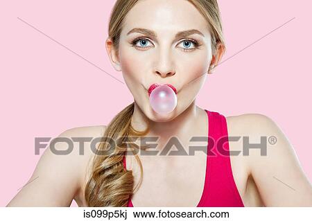 Stock Image - Young woman blowing bubble gum. Fotosearch