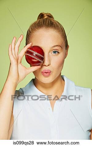 Stock Photo - Young woman holding cricket ball over her eye. Fotosearch