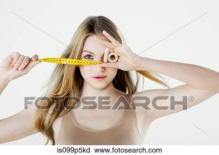 Stock Image - Young woman holding tape measure. Fotosearch
