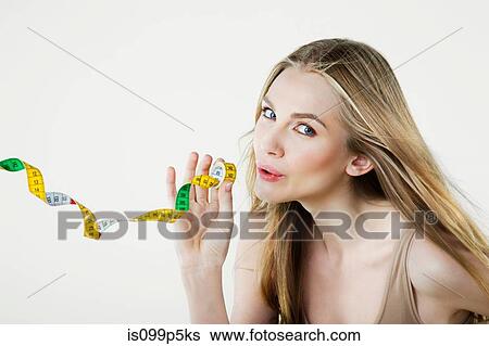 Stock Photograph - Young woman holding tape measure. Fotosearch