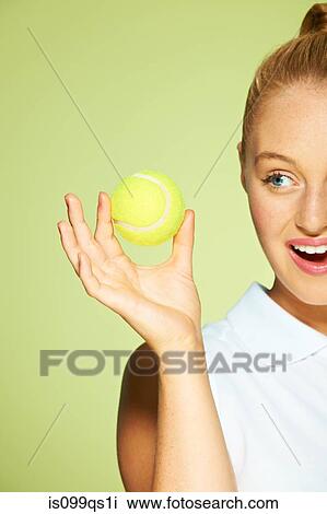 Stock Image - Young woman holding tennis ball. Fotosearch