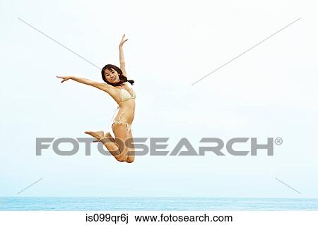 Young woman in bikini jumping on beach View Large Photo Image Stock Image - Young woman in bikini jumping on beach. Fotosearch