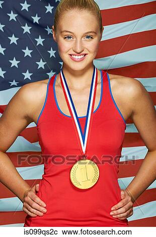 Stock Image - Young woman in front of USA flag with gold medal. Fotosearch