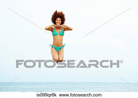 Young woman in turquoise bikini jumping on beach View Large Photo Image Stock Image - Young woman in turquoise bikini jumping on beach. Fotosearch