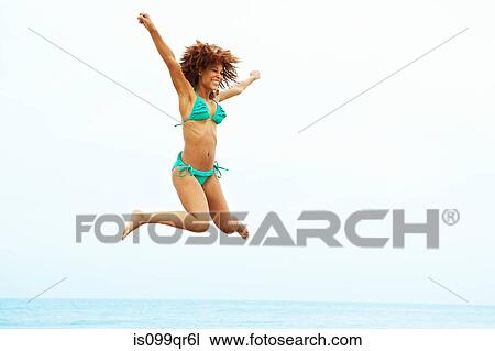 Young woman in turquoise bikini jumping on beach View Large Photo Image Stock Image - Young woman in turquoise bikini jumping on beach. Fotosearch