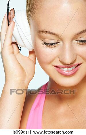 Young woman listening to music on headphones View Large Photo Image Stock Image - Young woman listening to music on headphones. Fotosearch