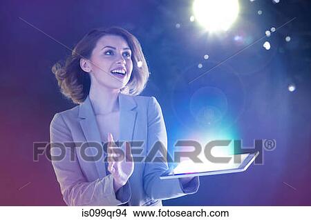 Picture - Young woman looking at lights coming from digital tablet. Fotosearch