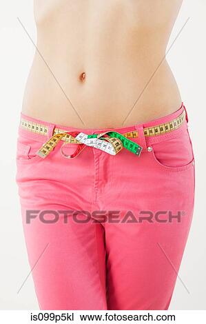 Young woman measuring waist with tape measure View Large Photo Image Stock Image - Young woman measuring waist with tape measure. Fotosearch