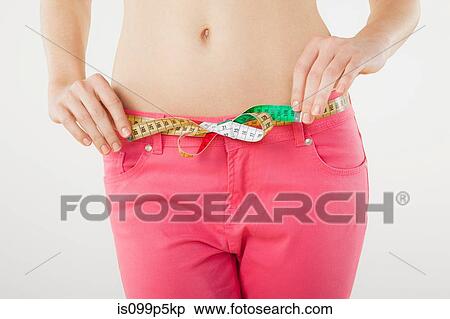 Stock Photography - Young woman measuring waist with tape measure. Fotosearch