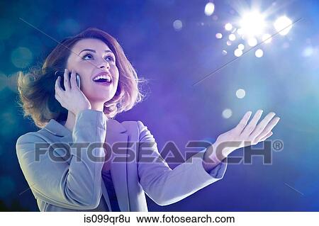 Young woman on cellphone, looking up at lights View Large Photo Image Stock Photograph - Young woman on cellphone, looking up at lights. Fotosearch