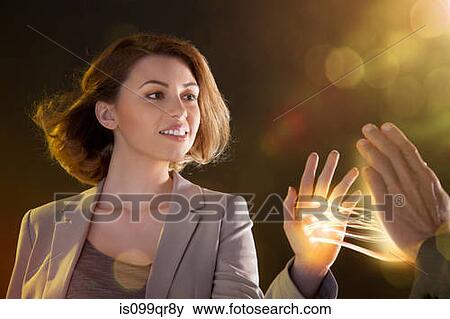 Stock Photo - Young woman touching light streams, connecting to another person. Fotosearch