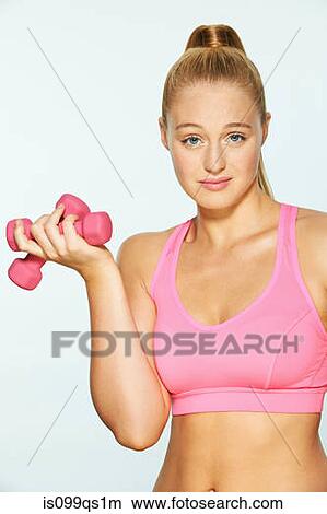 Young woman using hand weights, looking unimpressed View Large Photo Image Picture - Young woman using hand weights, looking unimpressed. Fotosearch