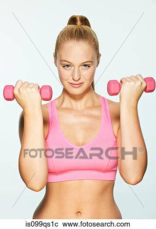 Stock Image - Young woman using hand weights. Fotosearch