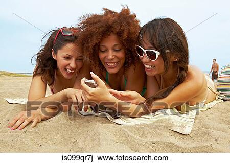 Stock Image - Young women sunbathing on beach. Fotosearch