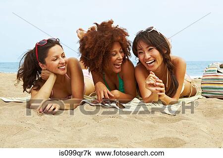 Stock Image - Young women sunbathing on beach. Fotosearch