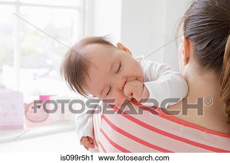 Baby girl sleeping on mother's shoulder View Large Photo Image Stock Image - Baby girl sleeping on mother's shoulder. Fotosearch