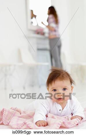 Baby girl with mother in background View Large Photo Image Stock Photography - Baby girl with mother in background. Fotosearch