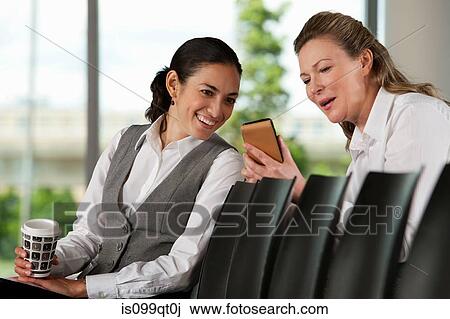 Stock Image - Businesswoman showing colleague smartphone. Fotosearch