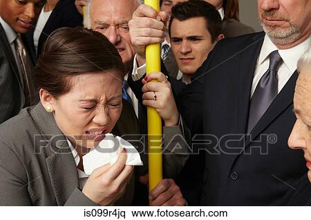 Stock Photography - Businesswoman sneezing on subway train. Fotosearch