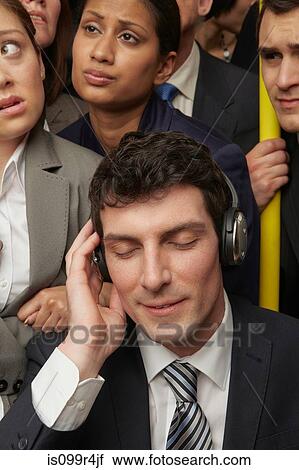 Stock Image - Businesswoman wearing headphones on subway train. Fotosearch