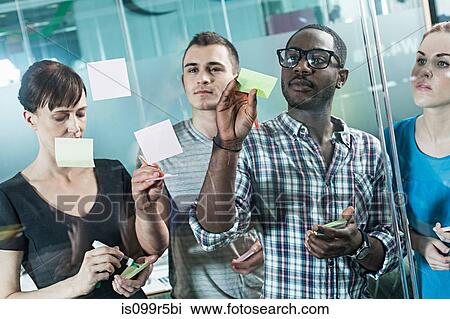 Colleagues writing on adhesive notes and sticking them to window View Large Photo Image Stock Image - Colleagues writing on adhesive notes and sticking them to window. Fotosearch