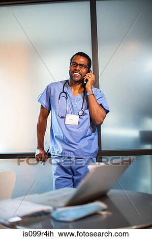 Stock Image - Doctor in office on cellphone. Fotosearch