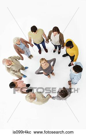 Stock Image - Group of people in a circle with woman in the middle, high angle view. Fotosearch