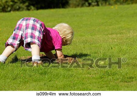 Picture - Little boy investigating molehill. Fotosearch