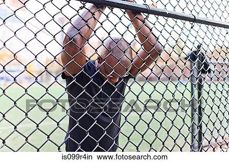 Picture - Man behind a chain link fence. Fotosearch