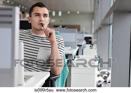 Man chewing pen at desk View Large Photo Image Stock Photograph - Man chewing pen at desk. Fotosearch