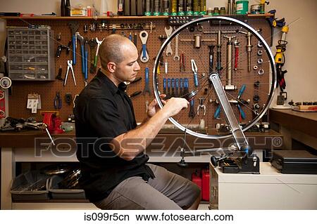 Man fixing bicycle rim in workshop View Large Photo Image Picture - Man fixing bicycle rim in workshop. Fotosearch