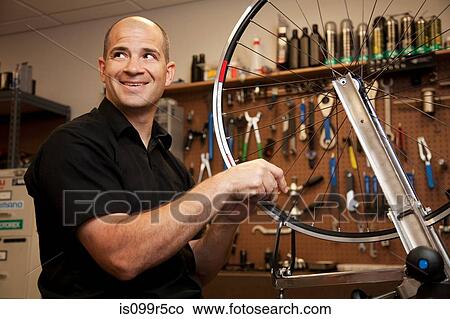Picture - Man fixing bicycle rim in workshop. Fotosearch