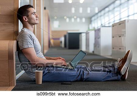 Man sitting on floor using laptop View Large Photo Image Stock Photograph - Man sitting on floor using laptop. Fotosearch