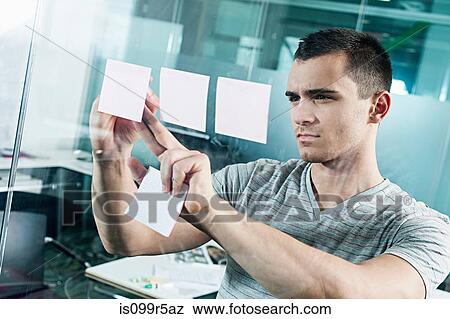 Man sticking adhesive note to window View Large Photo Image Stock Photo - Man sticking adhesive note to window. Fotosearch