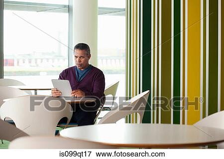 Stock Photo - Man using digital tablet in cafe. Fotosearch