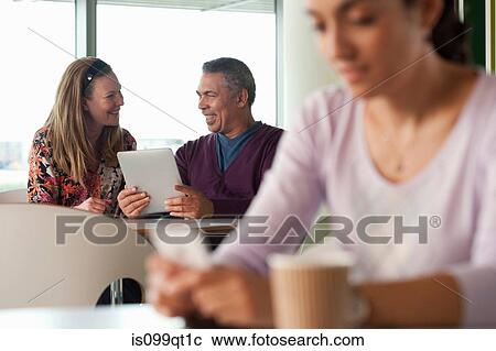 Stock Image - Man using digital tablet, woman texting in foreground. Fotosearch