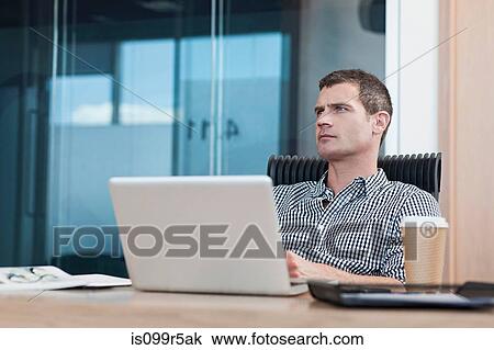 Stock Image - Man with laptop, looking away. Fotosearch