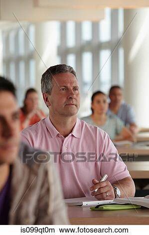 Picture - Mature students in class, man making notes. Fotosearch