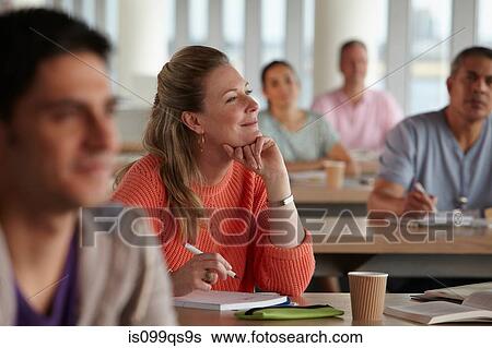 Stock Photograph - Mature students in class, woman with hand on chin. Fotosearch