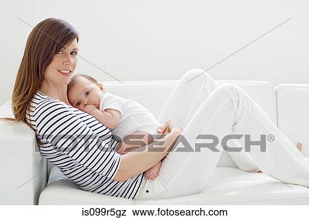 Stock Photo - Mother and baby girl on sofa. Fotosearch